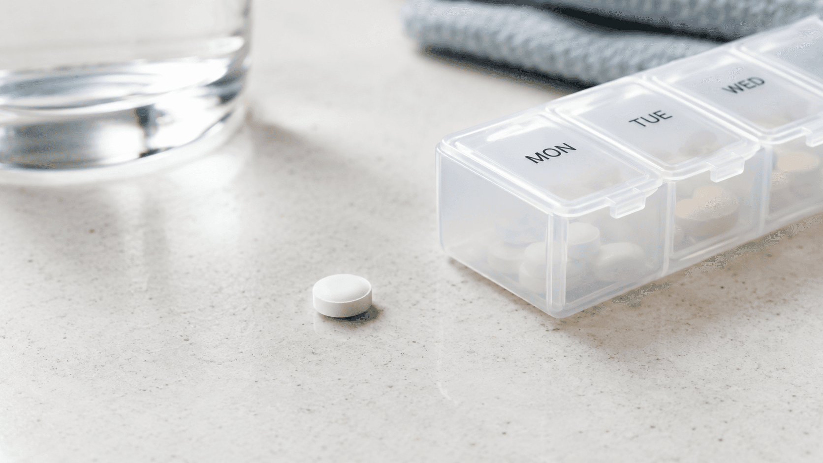 Unbranded white tablet and pill organiser on a clean countertop.