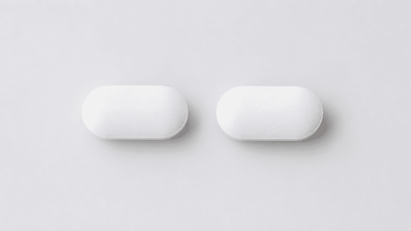 Two plain white tablets side by side on a clean white surface, photographed from above with no branding or packaging.